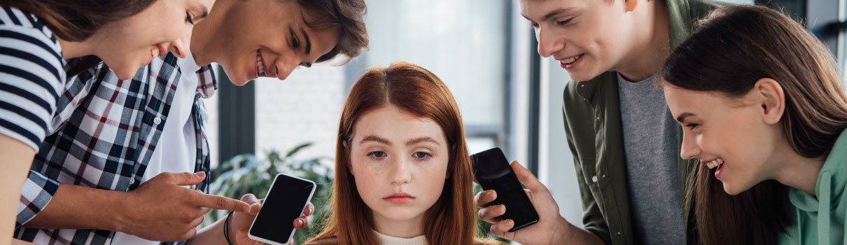 Jugendliche wird von Gleichaltrigen, die ihr Handy in den Händen halten geärgert